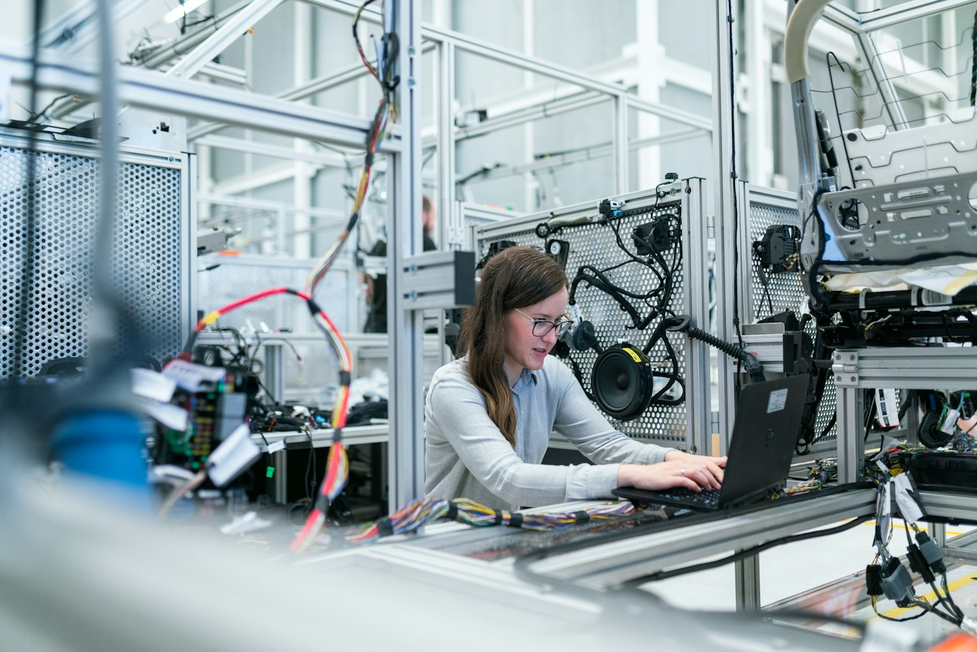 A woman engineer working at a laptop beside laboratory test equipment